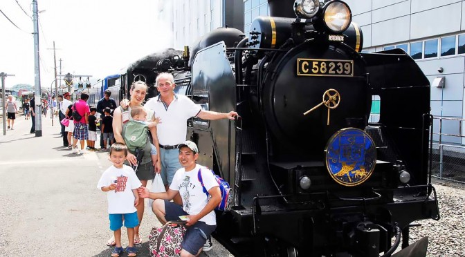 「ＳＬ銀河」をバックに笑顔で記念写真におさまる家族連れ＝16日、釜石駅