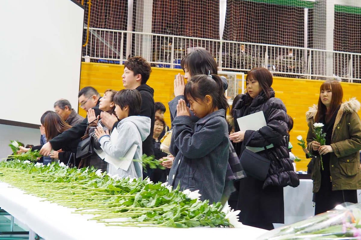 釜石市主催の震災５周年犠牲者追悼式で、犠牲になった家族や知人の面影を思い、手を合わせる参列者＝11日釜石高校体育館