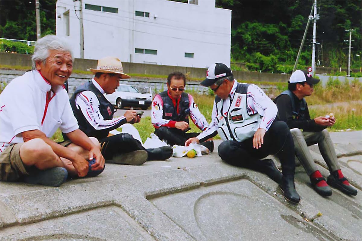 甲子川のアユを求めて訪れた遠来の釣り仲間と談笑する鈴子さん（左端）