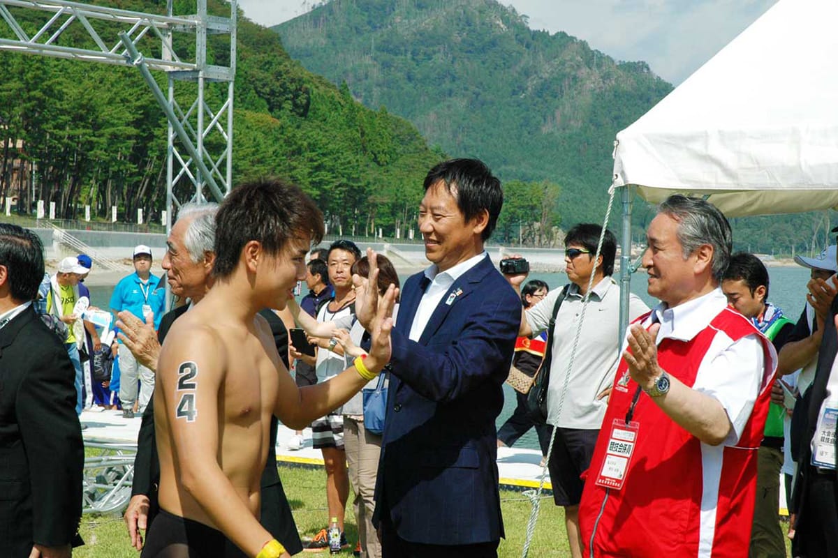 大会を視察に訪れた鈴木大地スポーツ庁長官（中）とハイタッチし、競技に向かう桑添陸選手