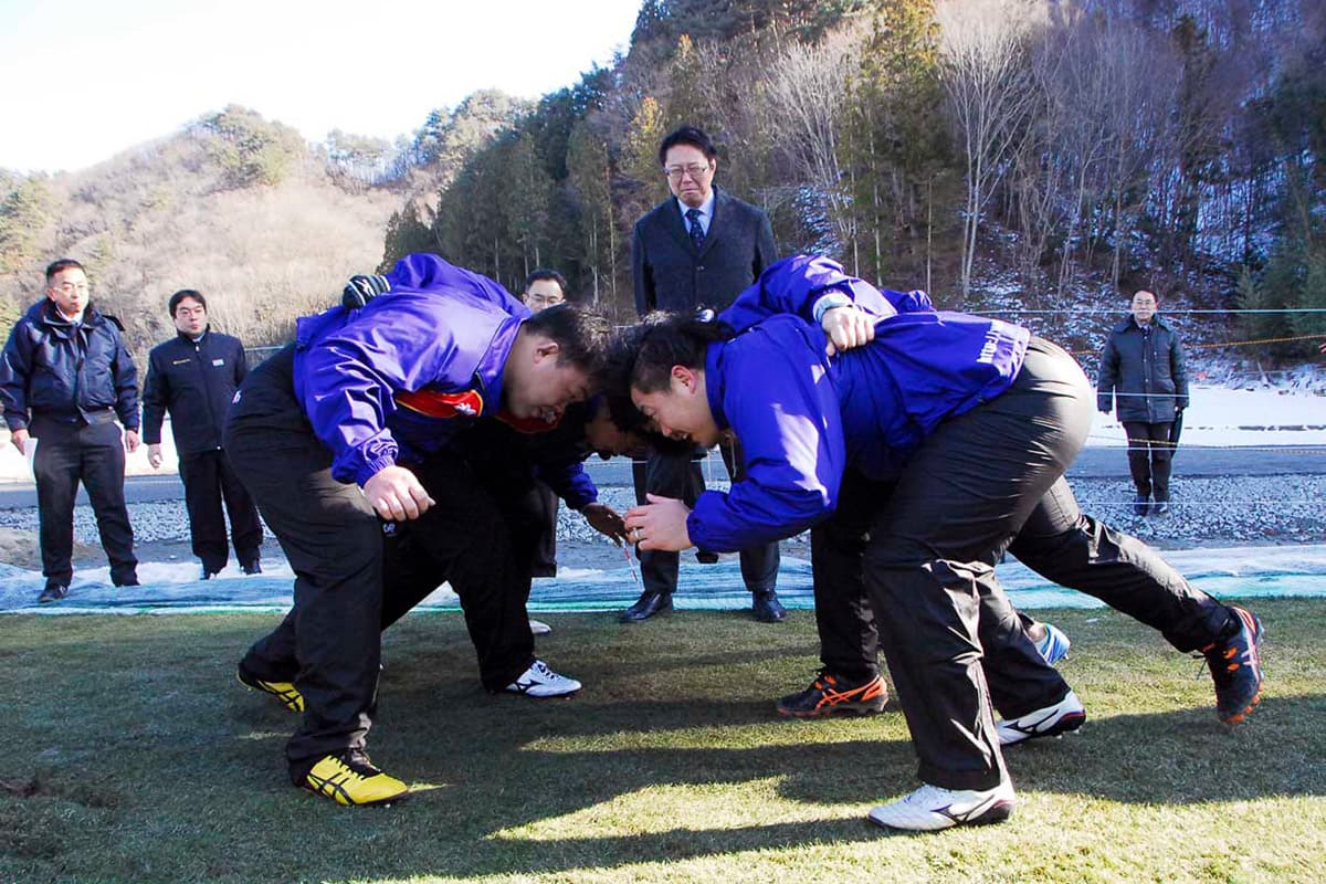 スクラムを組み、釜石鵜住居復興スタジアムに敷く芝生の感触を確かめる釜石ＳＷの選手ら