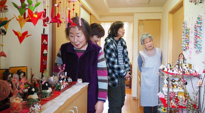 平田復興住宅の玄関を彩るひな飾り。震災後、二川さん（右）が集めた約30点が、心温まる世界をつくり出す
