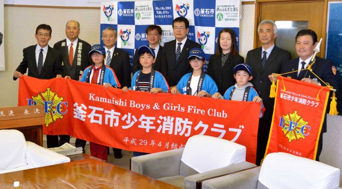 坂本さん（左端）が寄贈した装いで横断幕を掲げる「釜石Ｂ・Ｆ・Ｃ」の児童と関係者