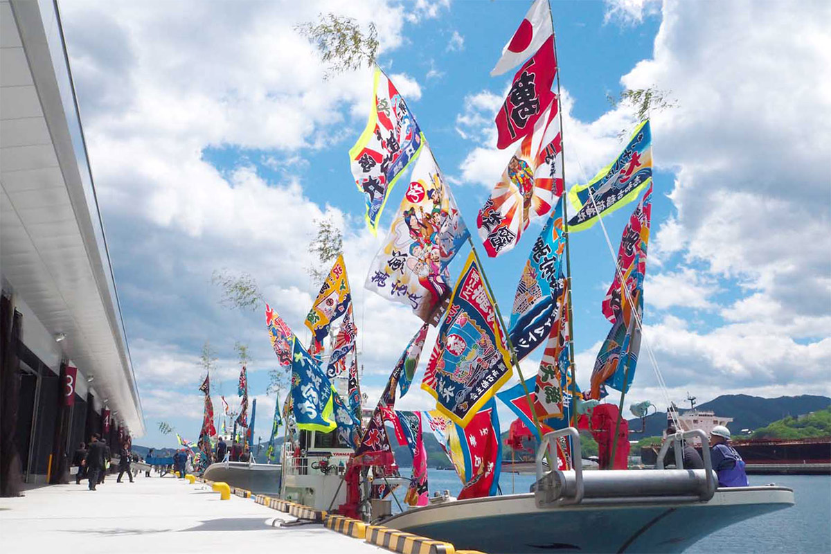 式典には漁師らも祝いの大漁旗を掲げて新しい魚市場に駆け付けた