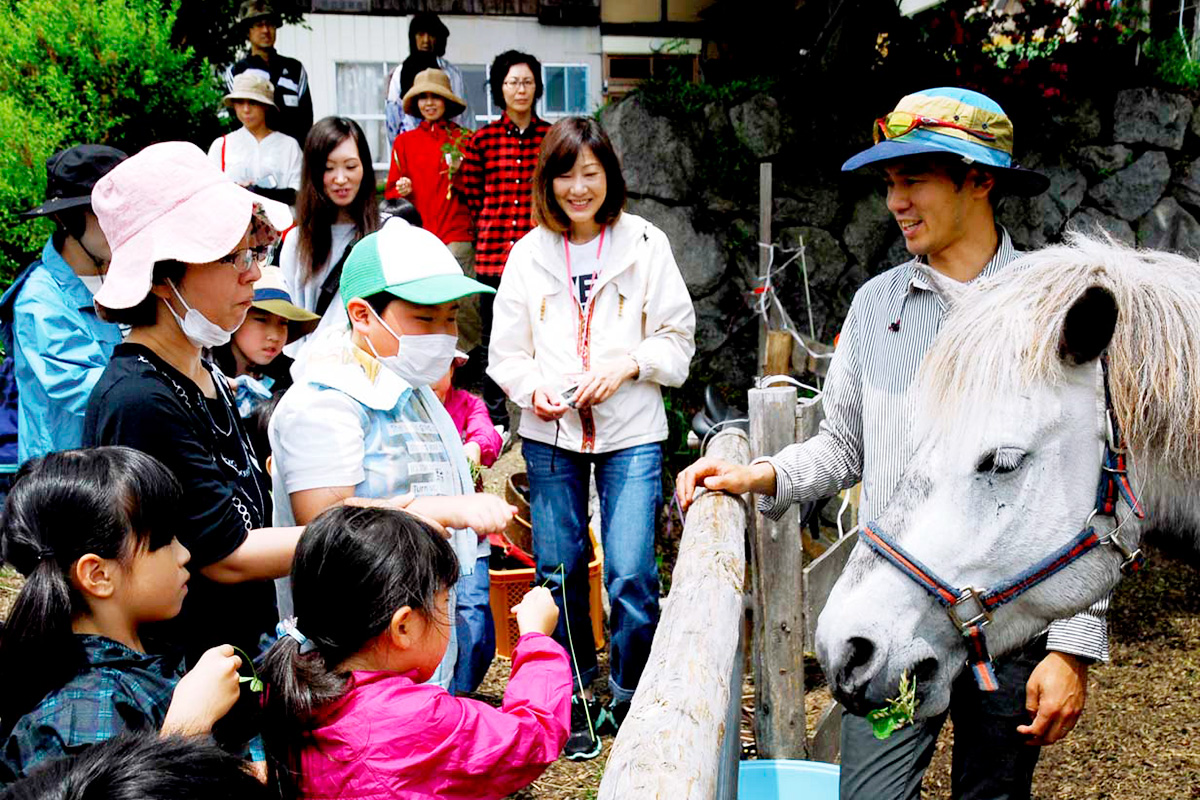 三陸駒舎の黍原豊さん（右）に教わりながら馬との触れ合いを楽しむ親子ら