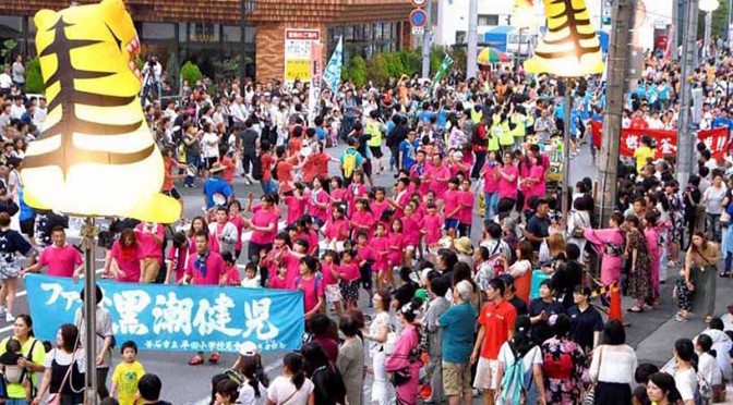 「ファイト黒潮健児」の横幕を掲げて行進する平田小の児童ら。沿道では約７千人の見物客が声援を送った