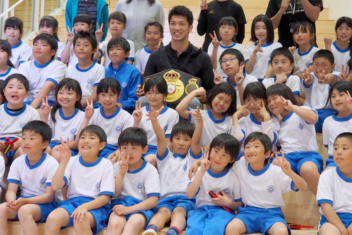 やさしい笑みの村田選手を囲んで「はい、チーズ」。子どもたちは笑顔を広げた