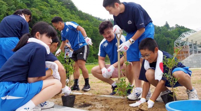 完成間近のスタジアム内にある花壇にドウダンツツジを植える釜石東中の１年生と釜石ＳＷ選手ら