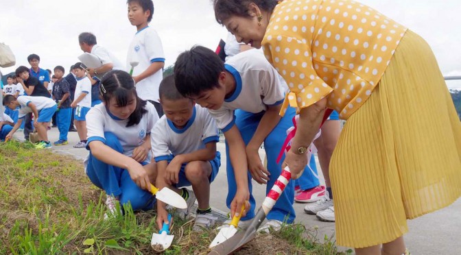 鵜住居小児童と協力してキリの苗木を植える一冊の会会員（右）