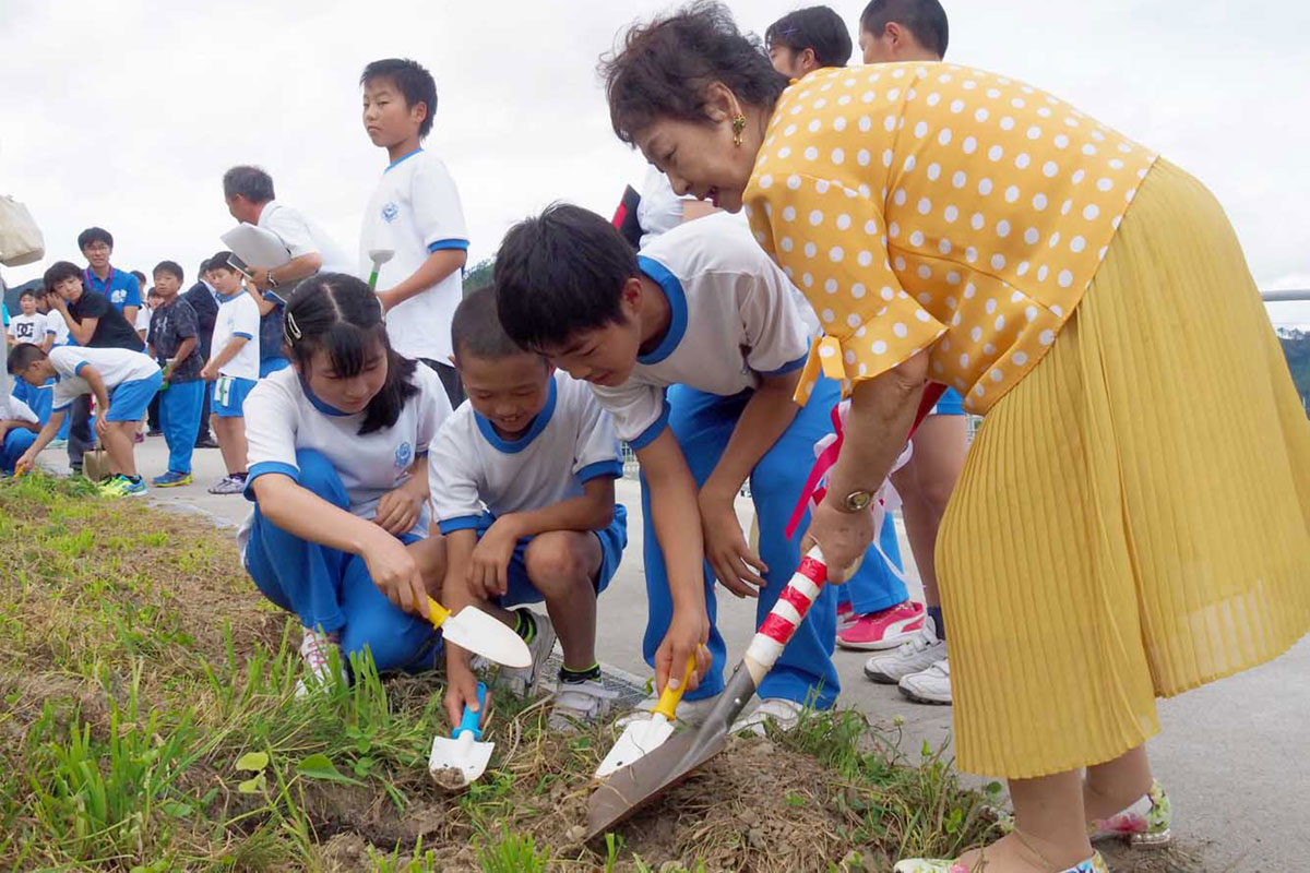 鵜住居小児童と協力してキリの苗木を植える一冊の会会員（右）