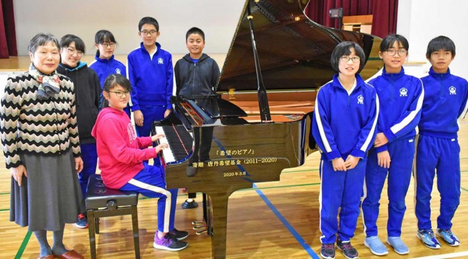 「希望のピアノ」を喜ぶ唐丹小高学年の児童と「唐丹希望基金」の高舘代表（左）