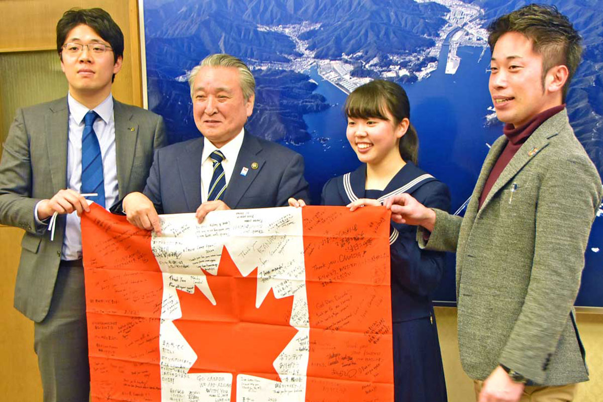 感謝の寄せ書きを手にカナダに留学する菊池莉歩さん（右から２人目）