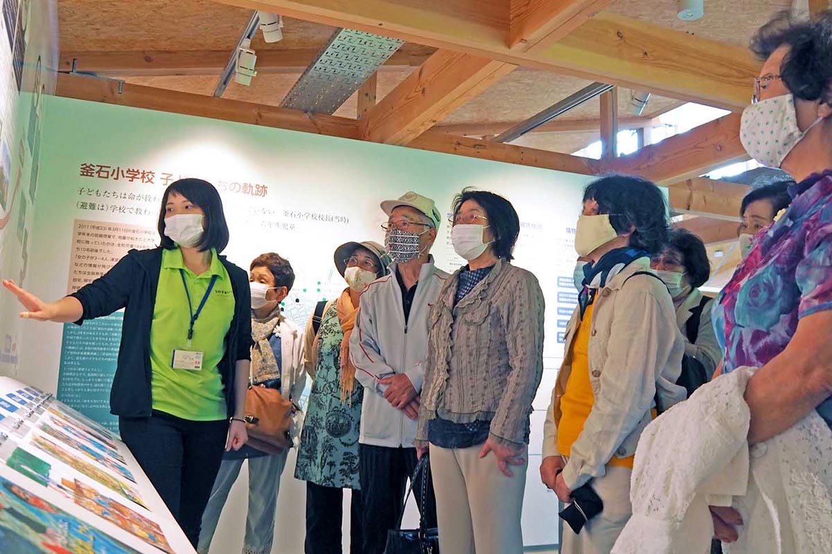 いのちをつなぐ未来館を見学する平田いきいきサークルの会員。川崎さん（左）の説明に耳を傾けた