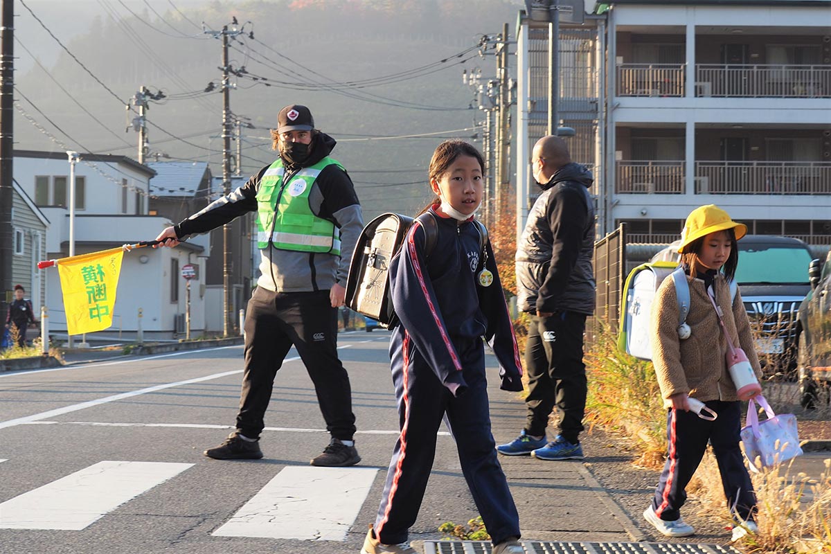 通学路の安全、がっちり！「横断中」の旗を手に児童の登校を見守るモーガン・ミッチェル選手