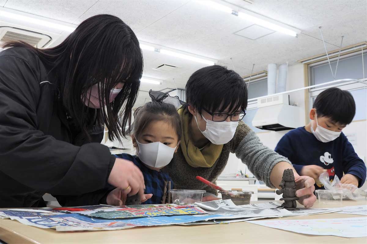参加者が作った置物などの仕上がりを確かめる澤田さん（右から２人目）