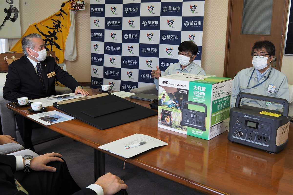 寄贈した蓄電池などを前に、野田市長（左）と懇談する浦島工場長（中）ら