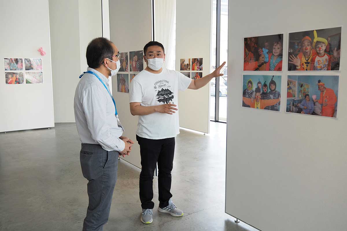 来場者に展示写真やクラウン活動を説明する梅沢さん（右）
