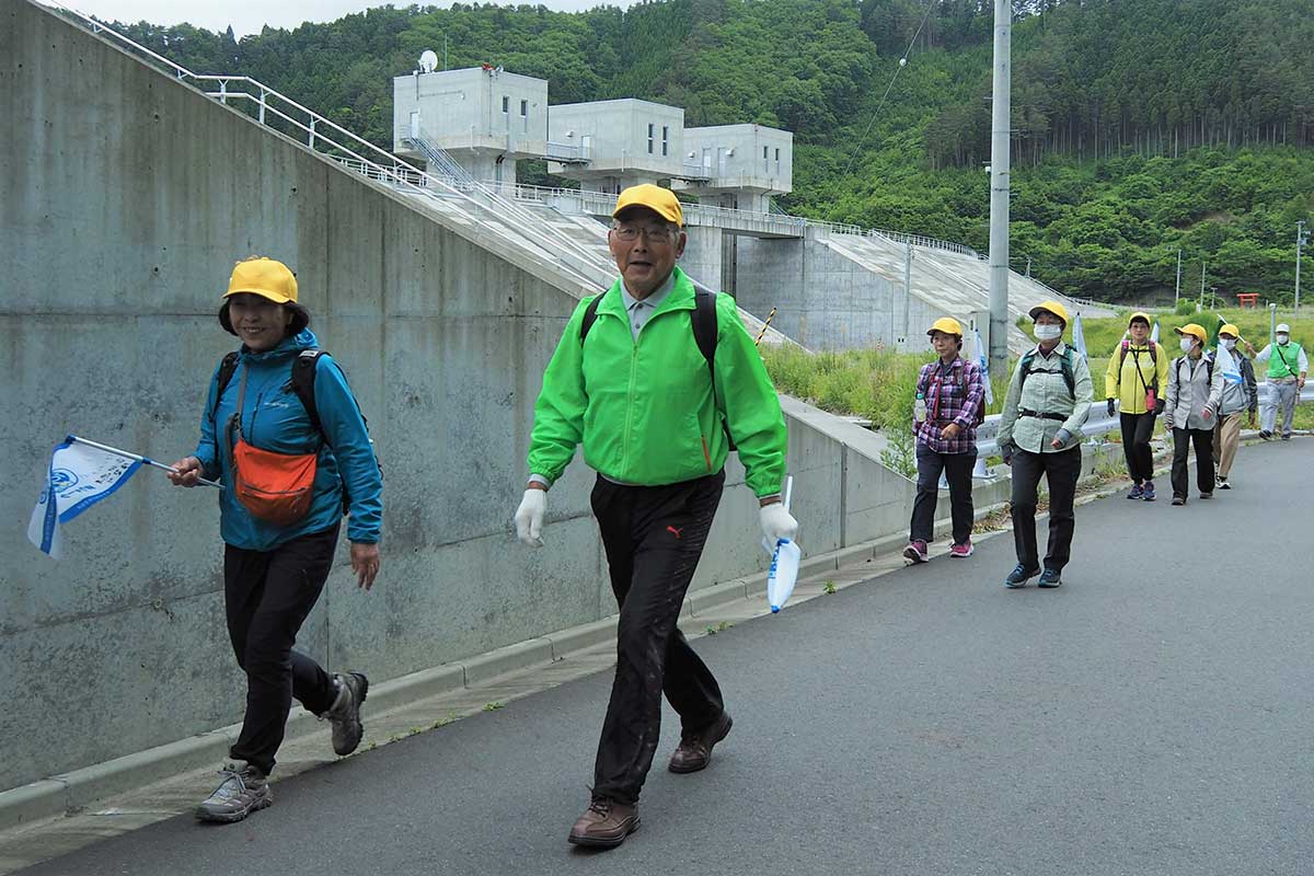 唐丹町に整備された防潮堤沿いを歩く釜石市協会員ら。余裕の笑顔が見える