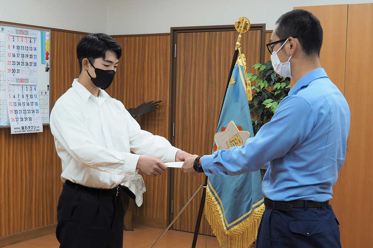 田中課長から指定書を受け取り交通安全意識を高める浦島君（左）