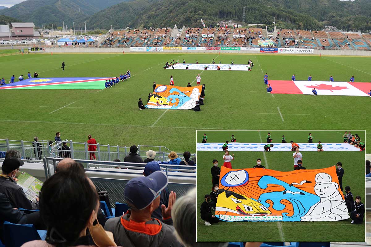 虎舞、大観音、ラグビーボールなどが描かれた釜石の大きな絵（右下拡大）。Ｗ杯で試合が中止になったナミビア、カナダ国旗とともに披露された