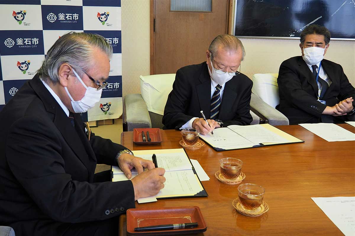 野田市長（左）と丸木会長（中）が協定書に署名した