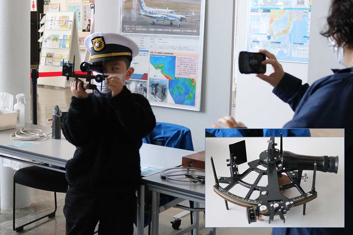 自分の船の位置を知るための角度測定に使う「六分儀」を体験する子ども＝釜石海上保安部の展示