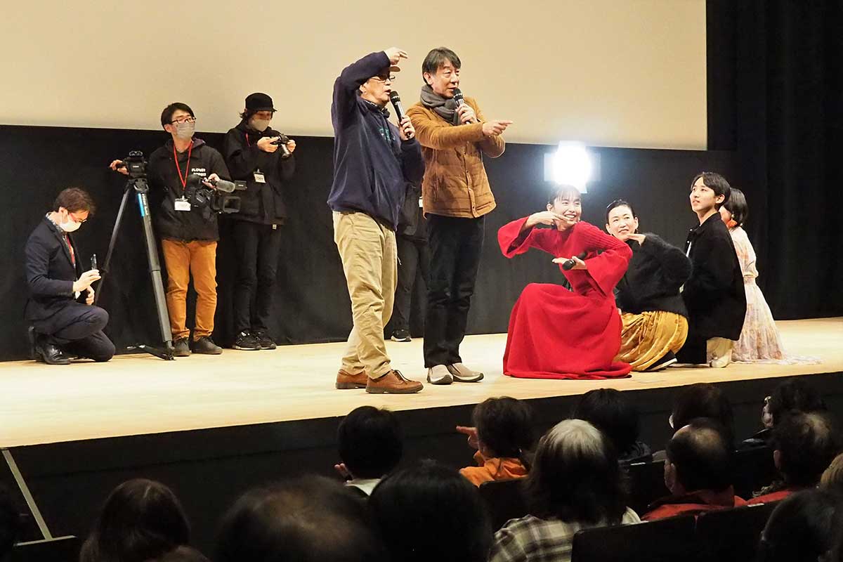 記念撮影で観客にポーズを指示する今関監督（前列左）ら出演者