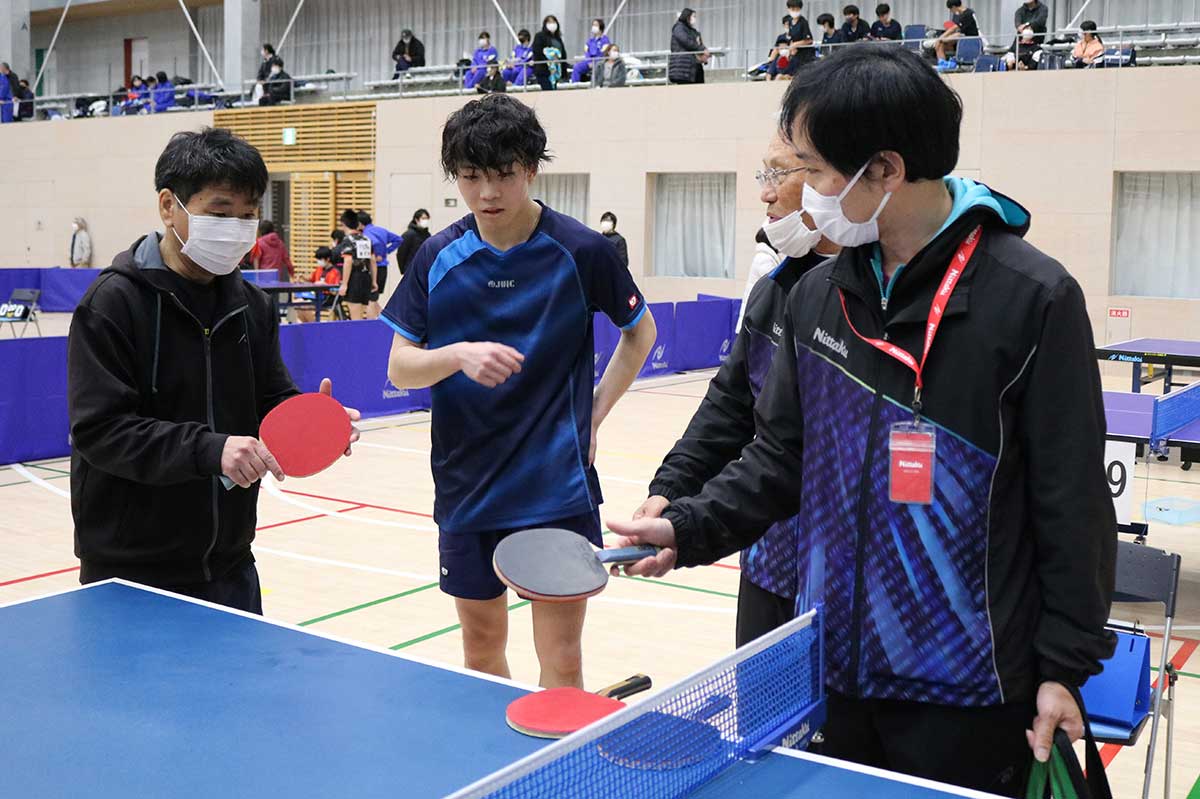 選手らは新しいモデルのラケットに興味津々。日本卓球の担当者（右）から説明を受けた