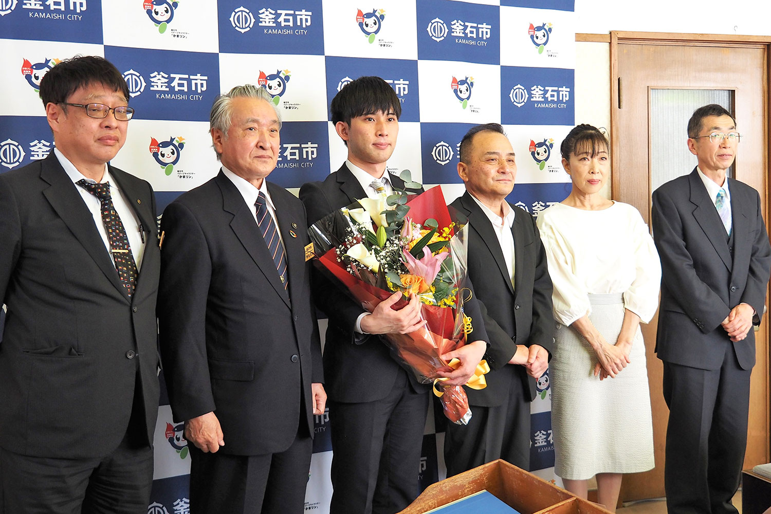 野田市長（左から2人目）らと記念撮影する小山さん（中央）＝釜石市役所