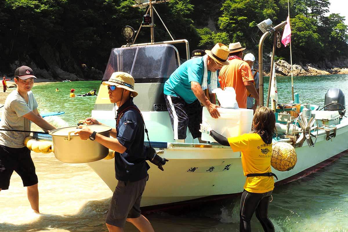 昼食のカレーライスや汁物を届けるのは地元漁師の船