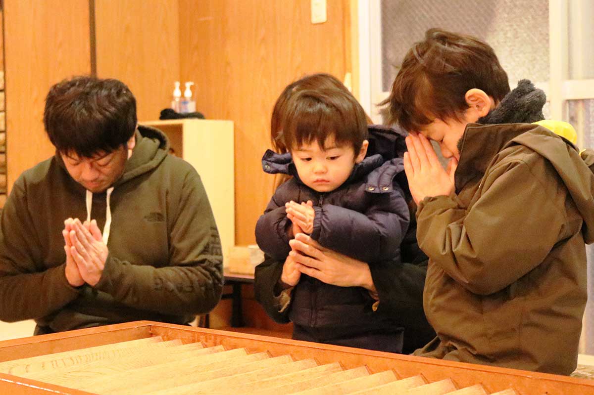 盛岩寺本堂で祈りをささげる家族連れ