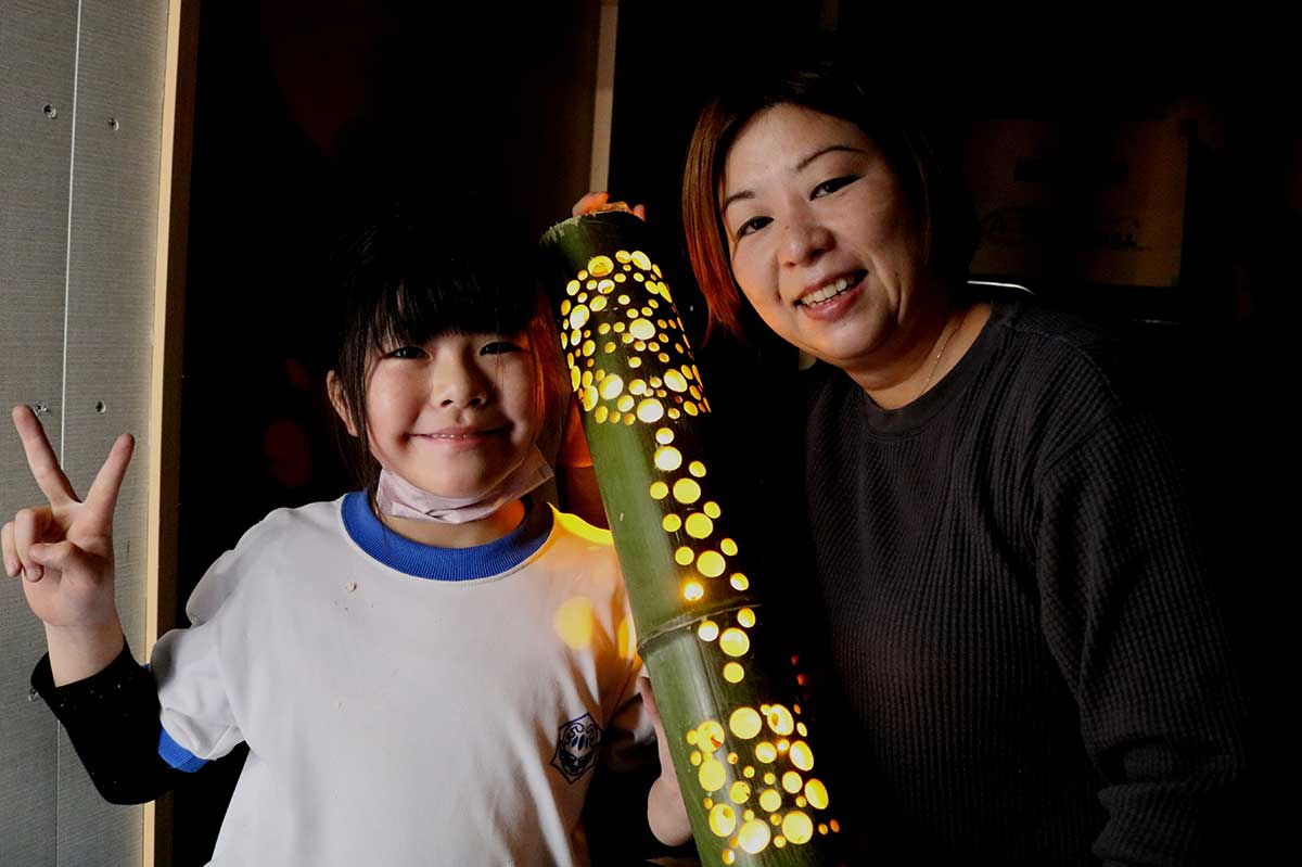 完成した竹灯籠に明かりを入れると美しい模様が浮かび上がった。母智恵さん（右）と笑顔を見せる智桜さん