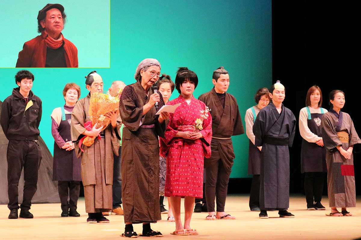 カーテンコールであいさつするおババ役の岩鼻美奈子さん（前列左）とタエ役の川端俐湖さん（同右）。写真左上は脚本の川端美津雄さん