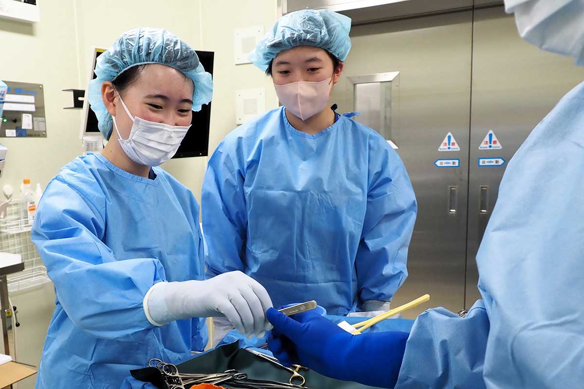 手術で使う器具を渡す「器械出し」を体験する生徒