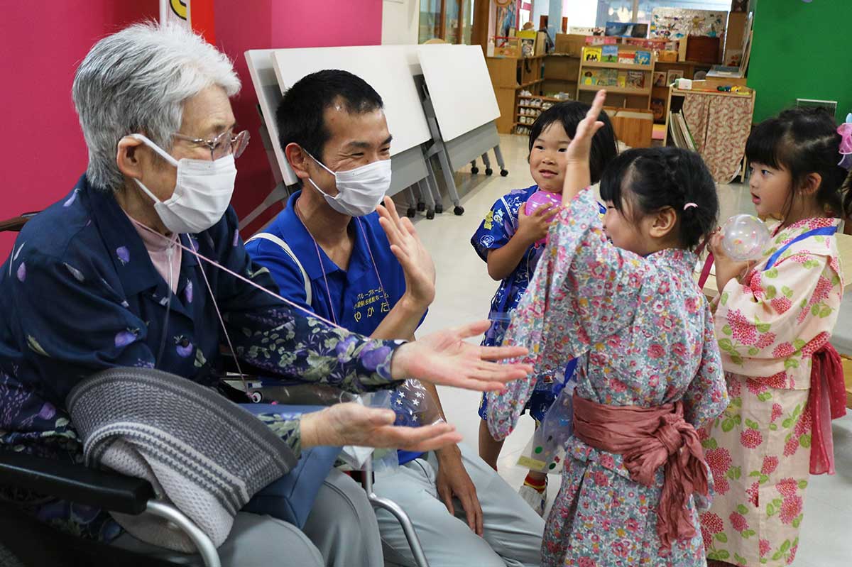 来園した高齢者施設の利用者、職員と交流する園児。笑顔の輪が広がる