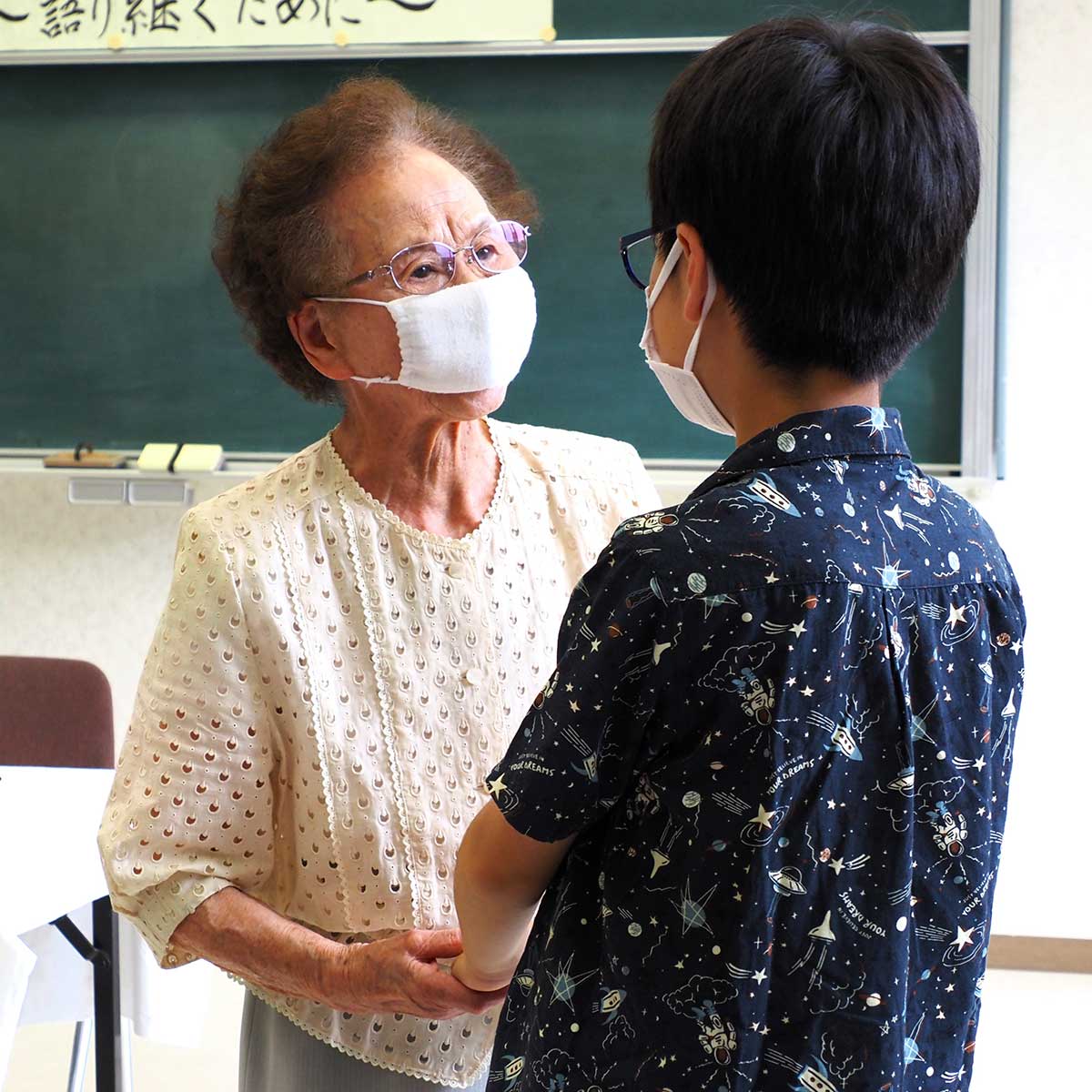 小学生の手を握って「平和を守って」と語りかける94歳の佐々木郁子さん