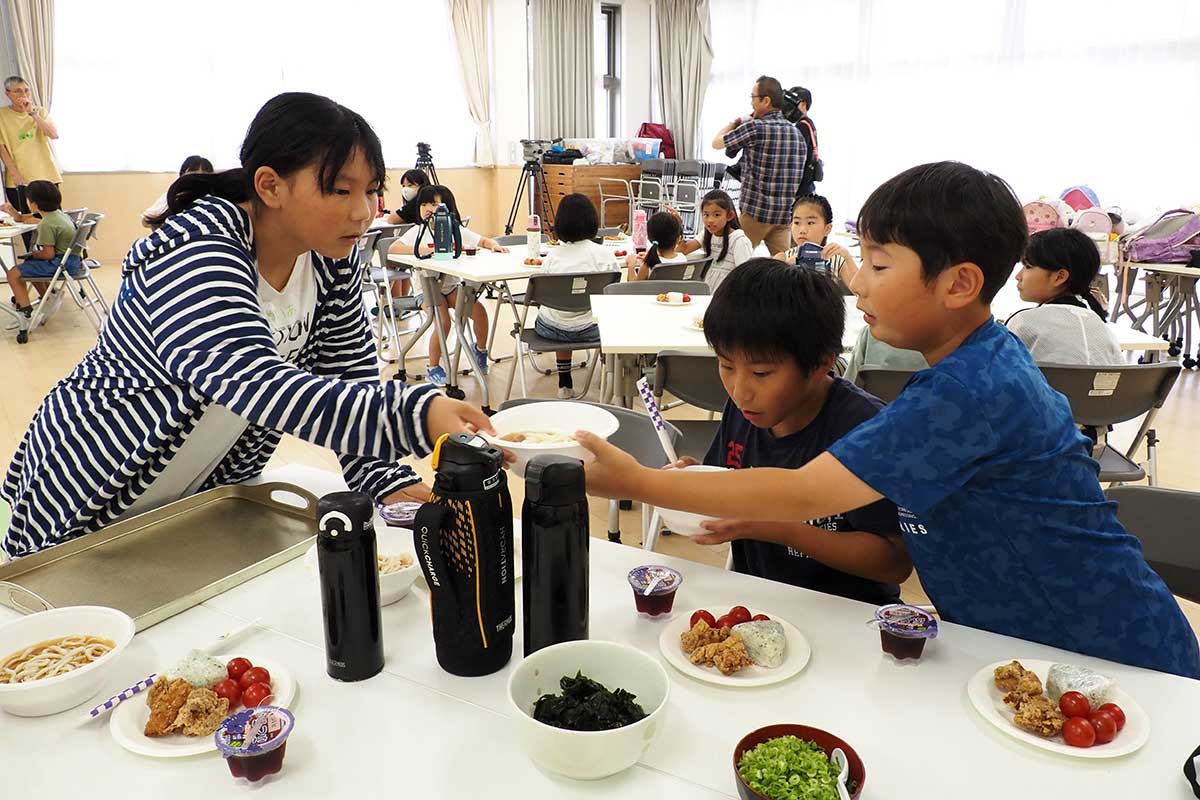 「はい、どうぞ」。高学年の児童が料理運びをお手伝い