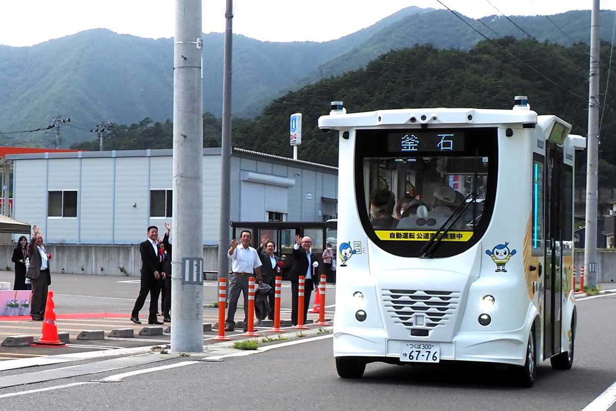 釜石市平田地区を走行する自動運転バスを関係者が見送る