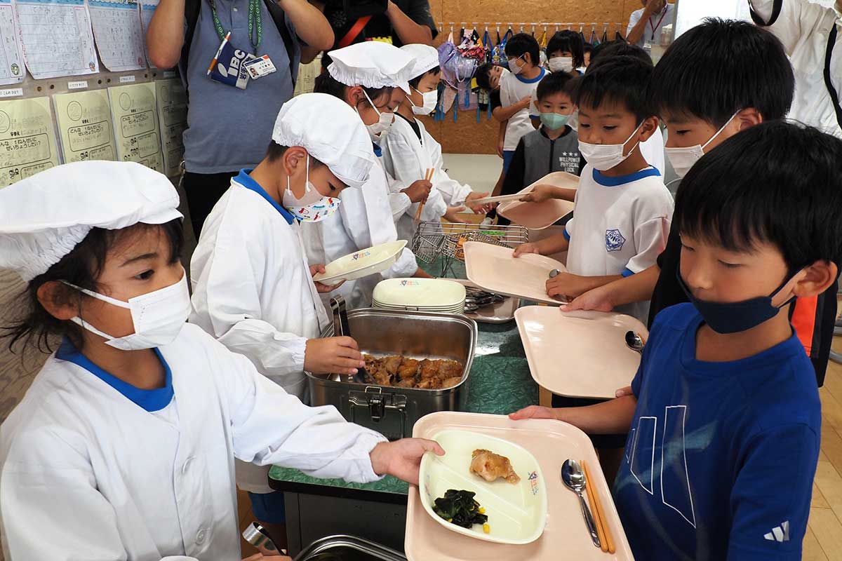 お楽しみの給食の時間。トレーを持つワクワク顔の列が続く