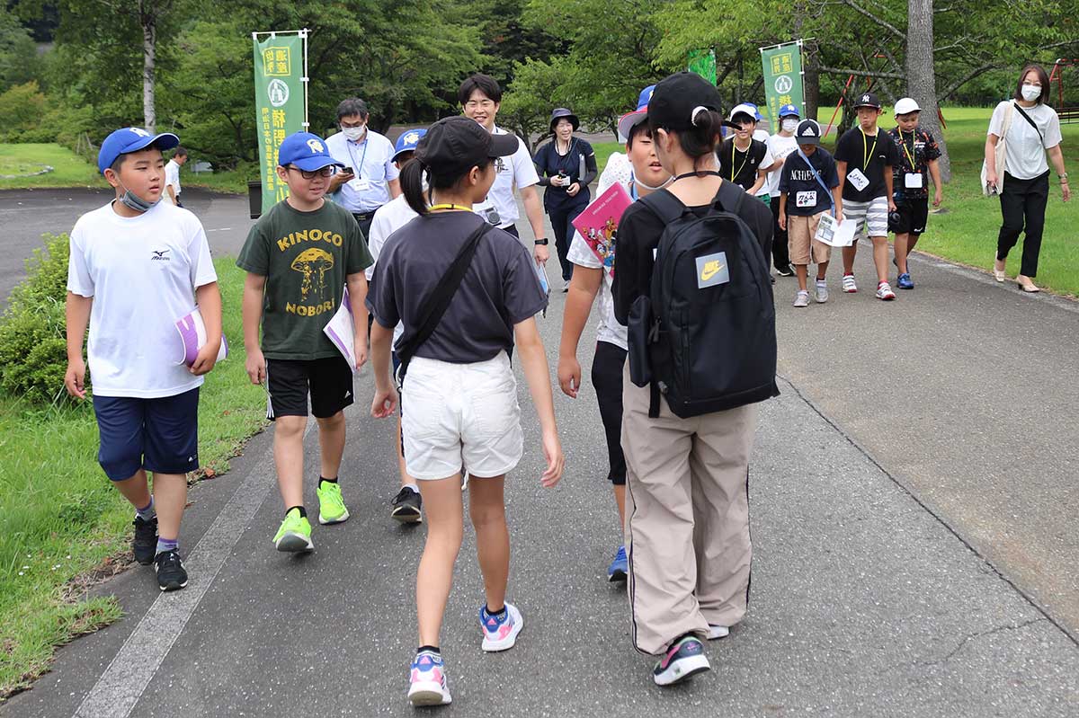 栗林小児童の案内で高炉場跡に向かう一戸南小の児童（青帽子）