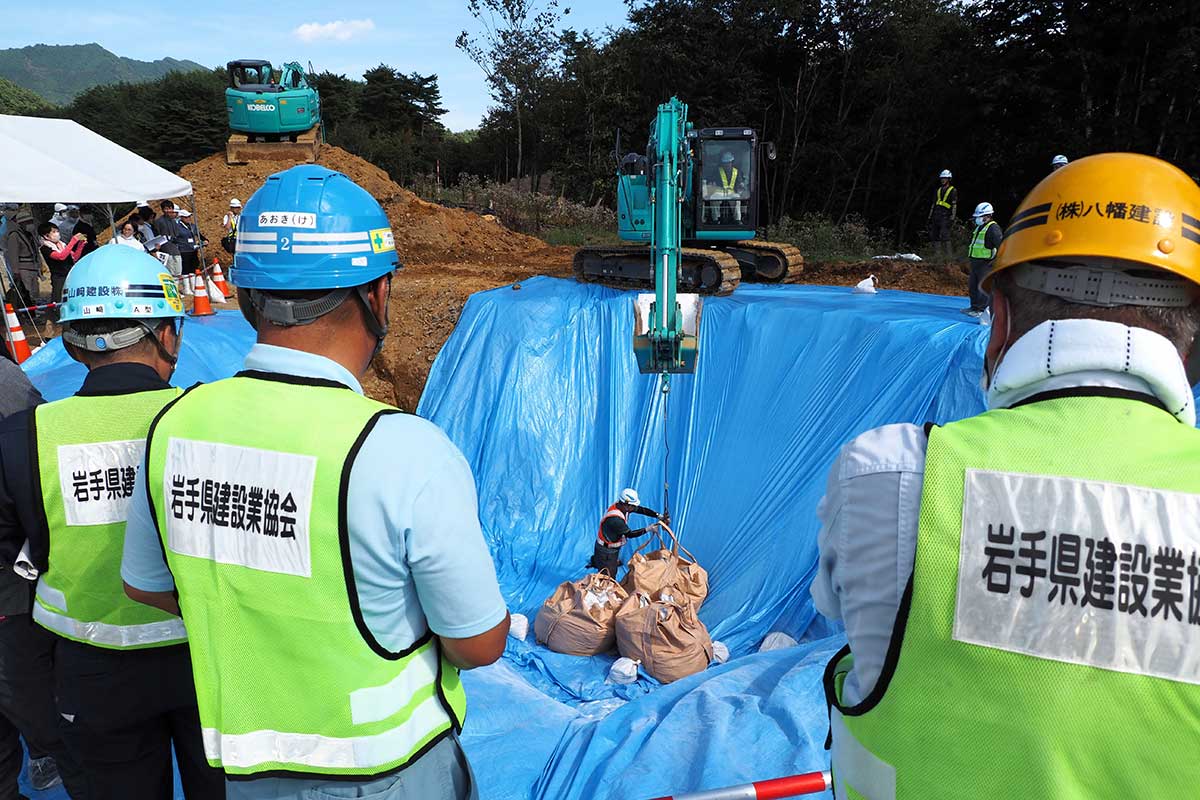 埋却作業を見守る建設業協会釜石支部の関係者ら