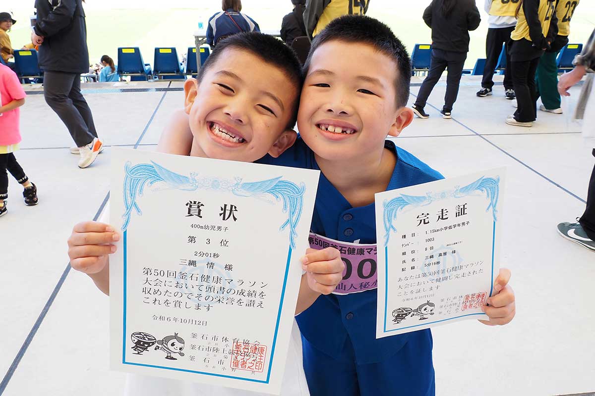 完走証を手に笑顔を見せる三縄高雅さん（右）と弟の情君