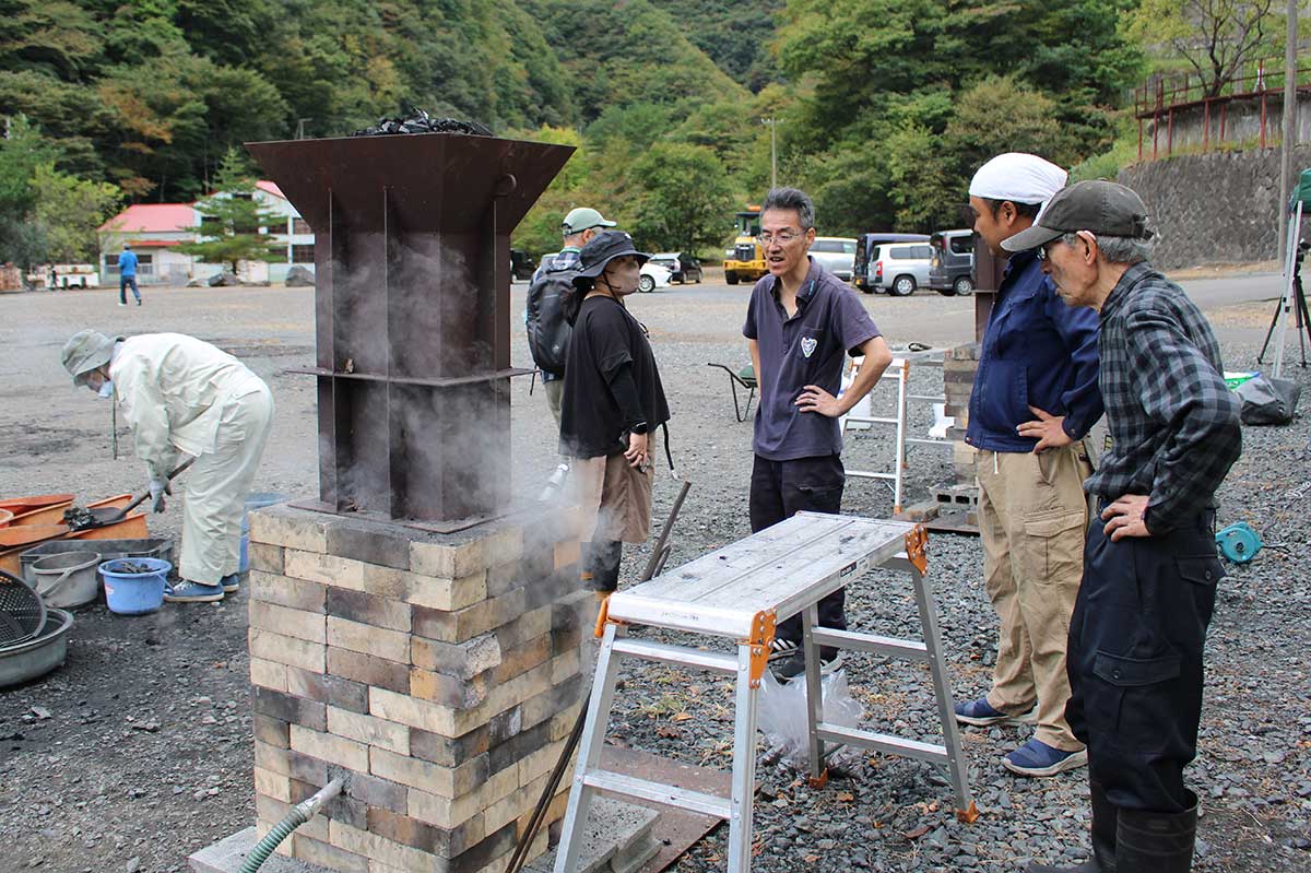 風を送りながら加熱中の炉。煙突口には投入した木炭が見える＝10月6日午前10時半ごろ