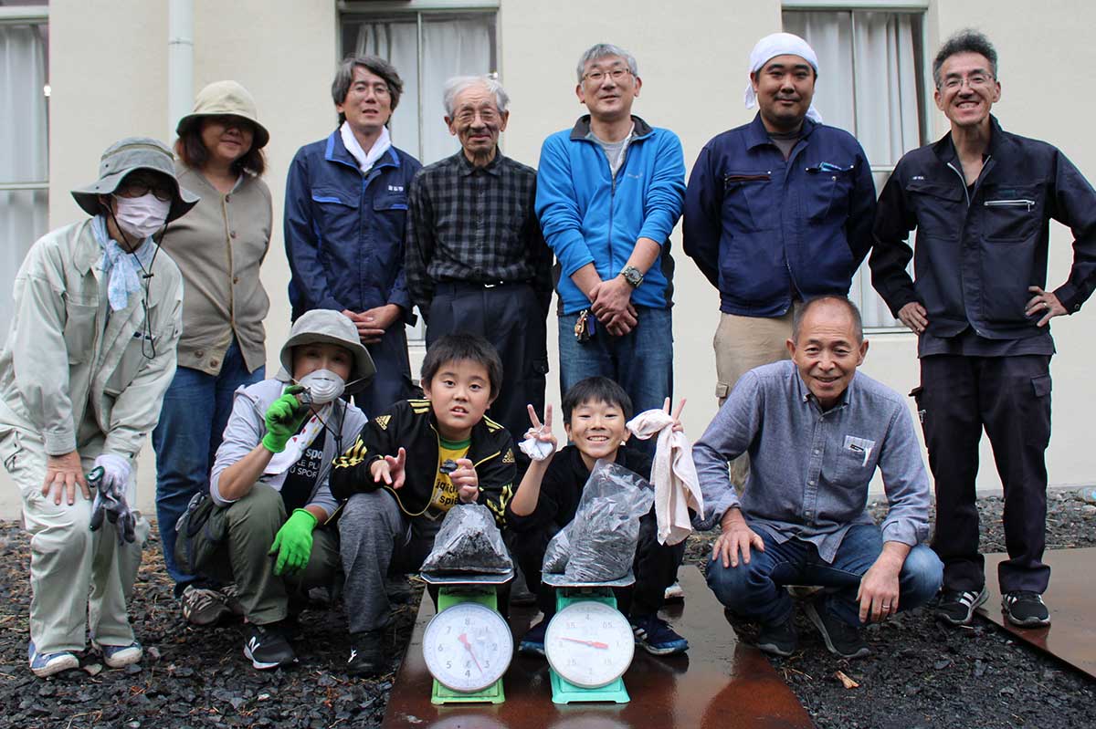 餅鉄からできた6.5キロの鉄を前に笑顔を輝かせる参加者