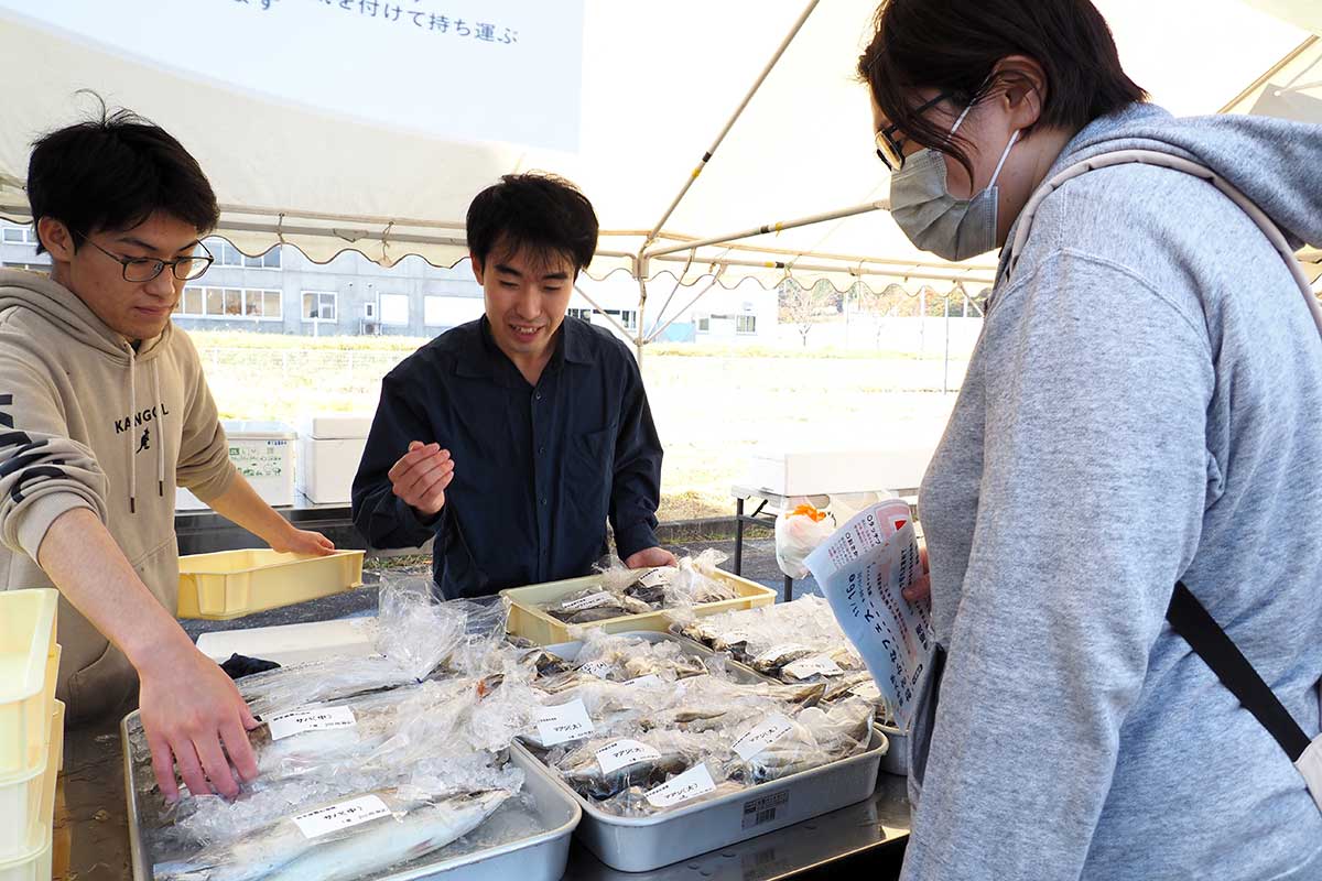 消費者となる買い物客に仕入れた魚種の説明をする髙山琢磨さん（中）