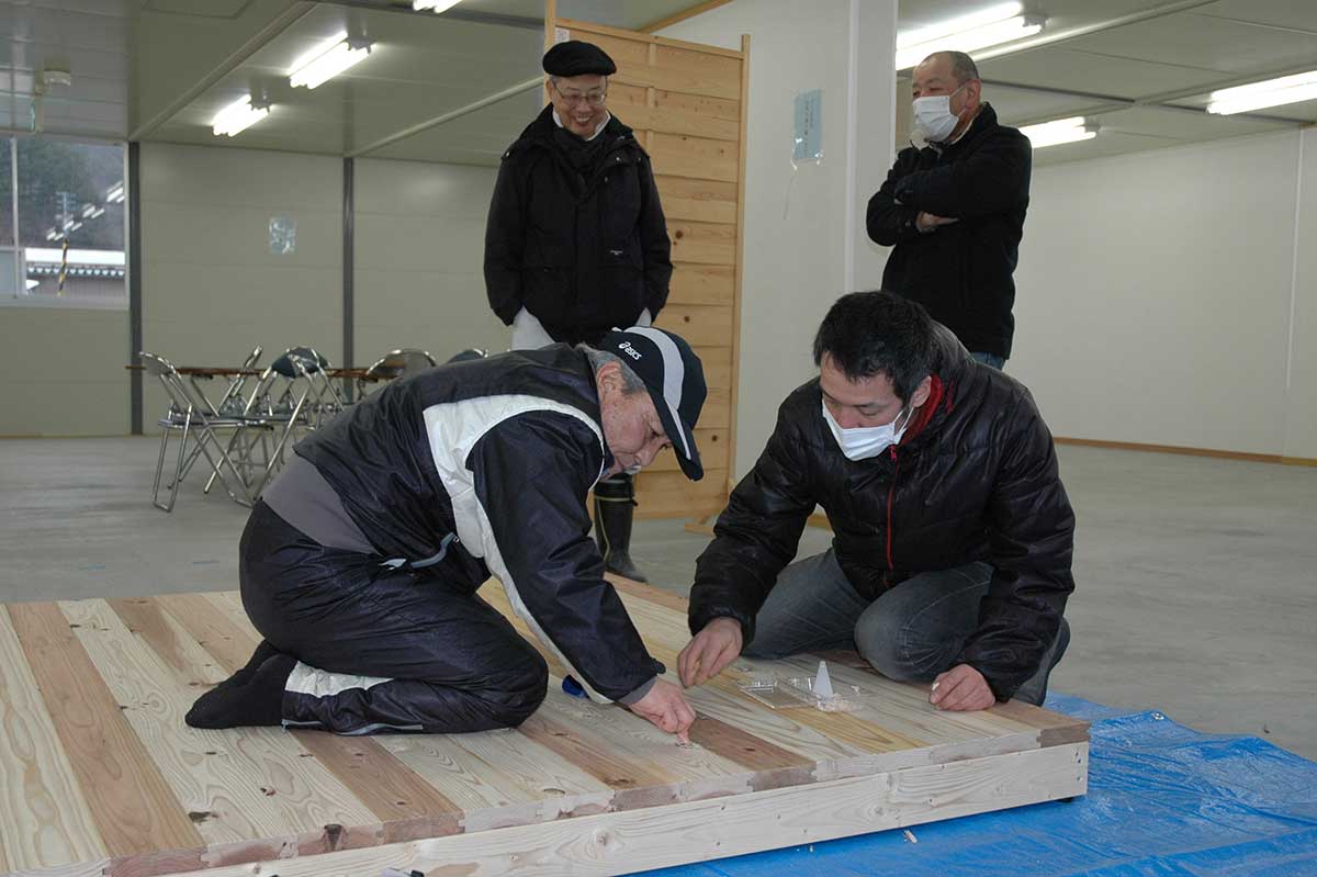 仮設団地の住民と平田パークホール用の簡易ステージを作る岩森勇児さん（手前右）