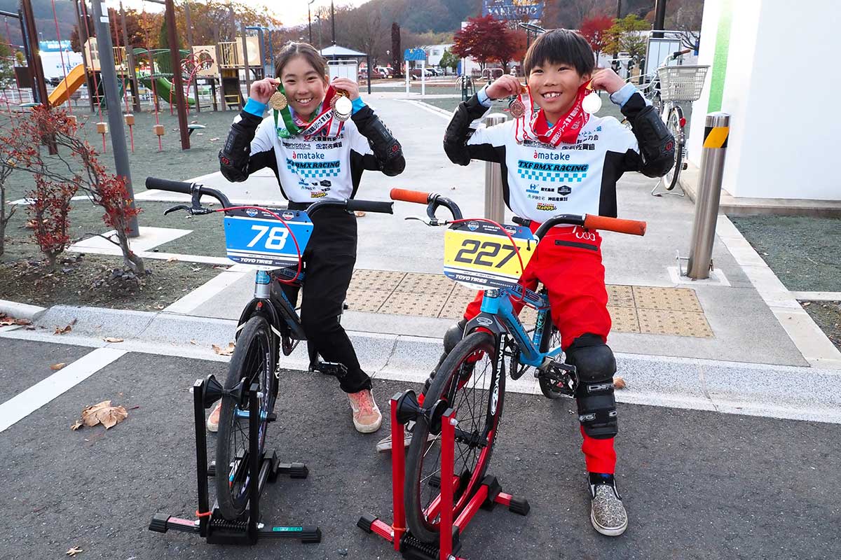 愛用する自転車に乗ってメダルを見せる越野杏音さん（左）、斗葵さん