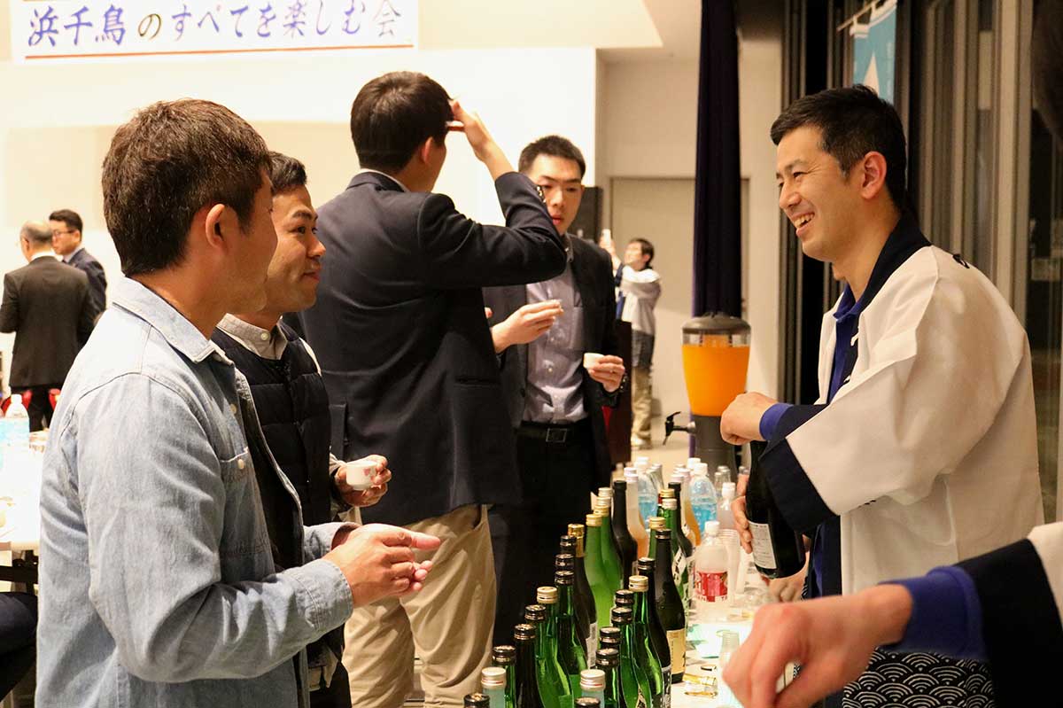 奥村康太郎杜氏（右）から各銘柄の特徴などを聞き、酒の試飲を楽しむ参加者