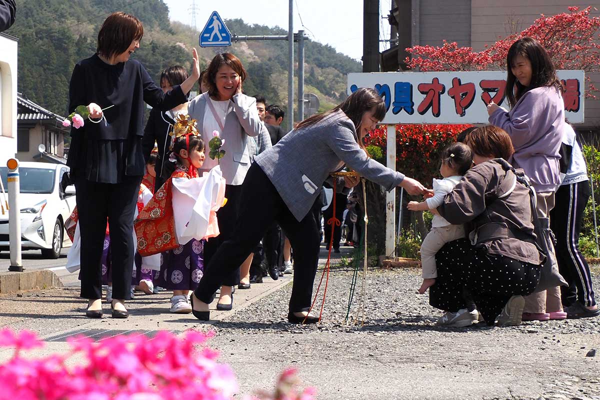お祝いに駆け付けた住民らに縁起物を手渡す