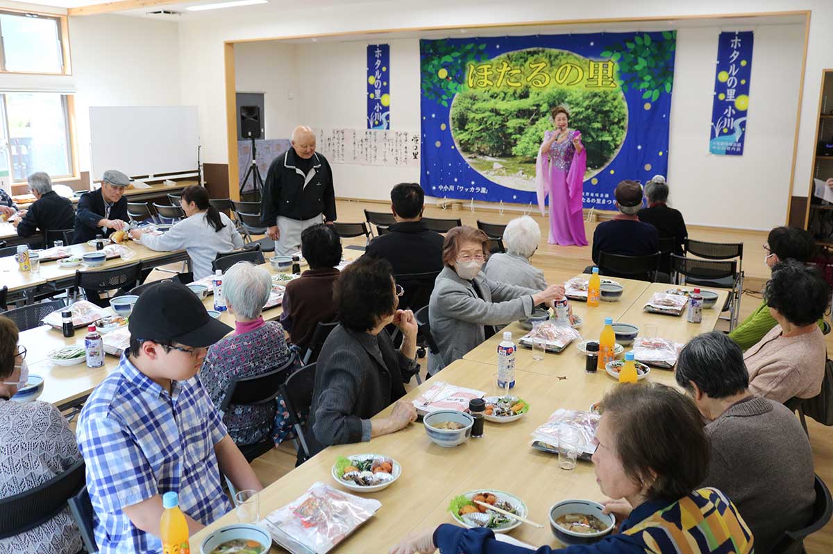 新築された「上小川・中小川集会所」のホールで歌や食事を楽しむ住民ら＝27日